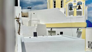 A white building with a blue dome and a bell tower. - Fira Heart Studios (Santorini)