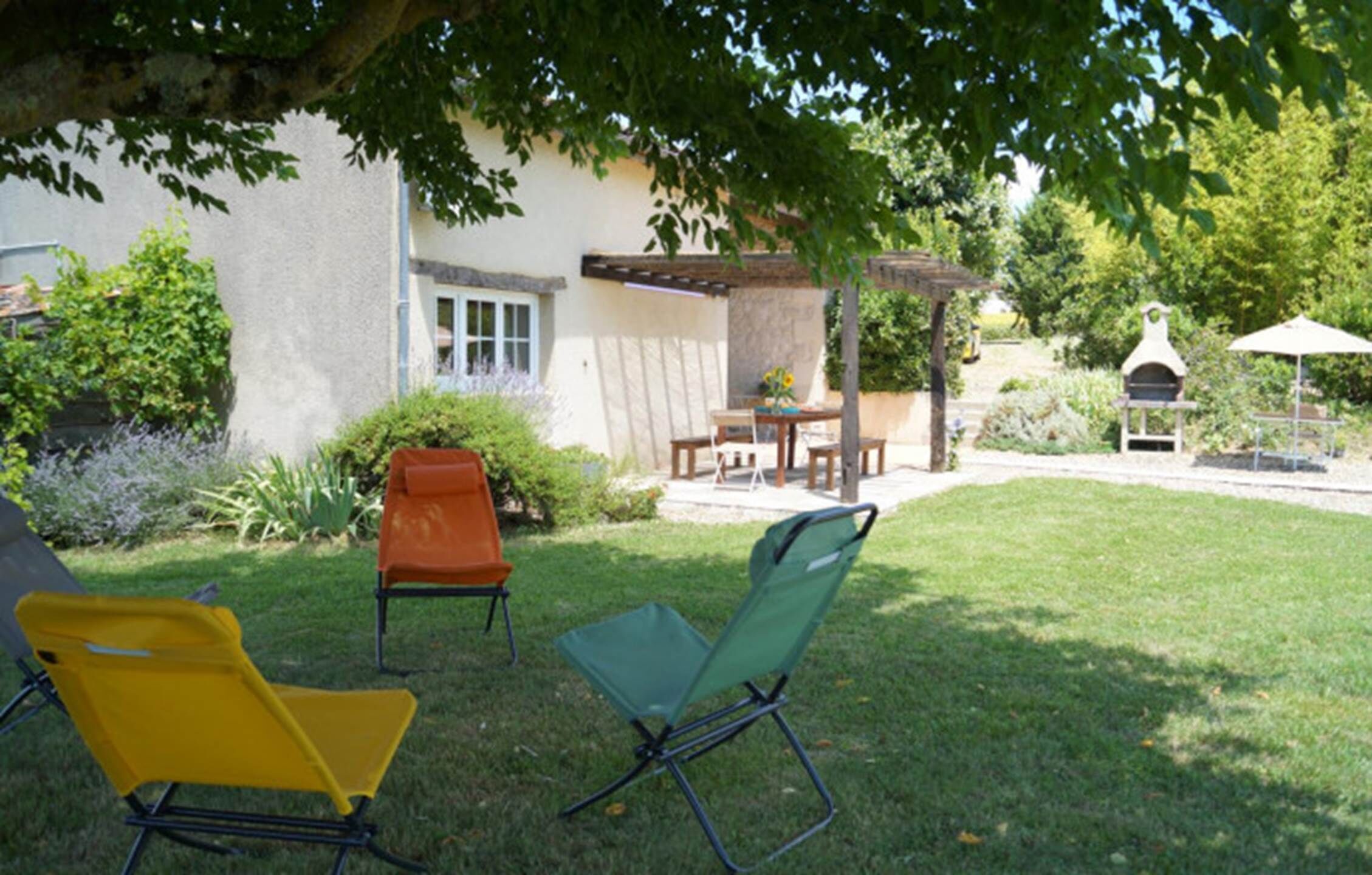 A patio with two folding chairs, a table, and a barbecue grill.