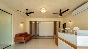 A modern lobby with a reception desk, a sofa, ceiling fans, and a large window. - Yellowstone Resort Arambol (Arambol)
