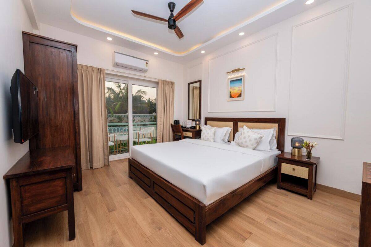 A bedroom with a wooden bed, a ceiling fan, a TV, and a balcony with curtains.