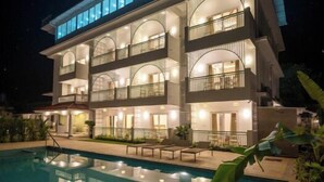 A multi-story hotel with a pool, balconies, and a well-lit facade. - Yellowstone Resort Arambol (Arambol)