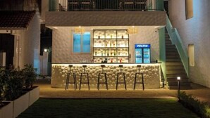 A two-story building with a balcony, a bar area with stools, and a staircase. - Yellowstone Resort Arambol (Arambol)