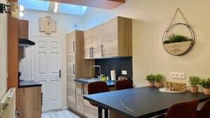 Una cocina moderna con armarios de madera, encimera negra y una mesa de comedor con sillas rojas.