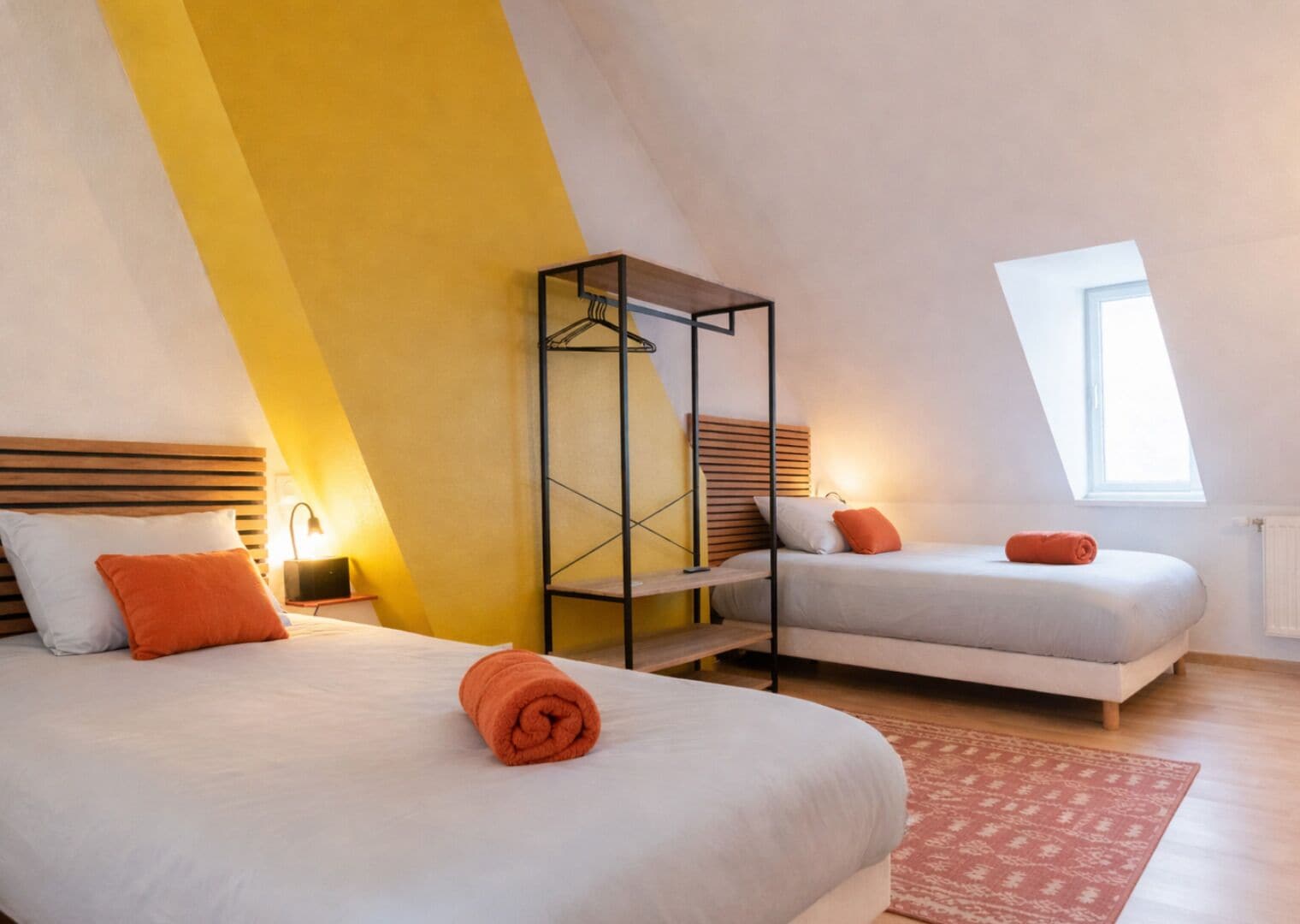 Camera da letto con due letti, una poltrona sospesa e un lucernario.