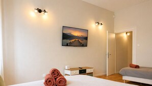 Una habitación de hotel con una cama, un escritorio, una silla, un cuadro y una puerta.
