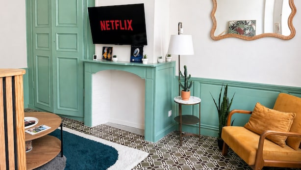 Una sala de estar con televisor, chimenea, sofá, mesa de centro y espejo.