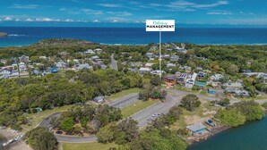 An aerial view of a coastal residential area with houses, a marina, and a road leading to the water. - Dreamtime Dune Studio (Fingal Head)