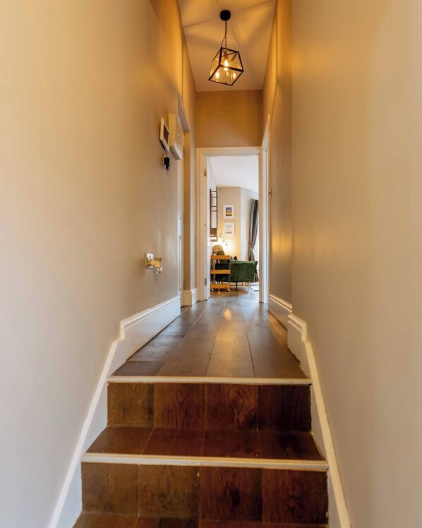 Un escalier avec des marches en bois et des moulures blanches menant à une pièce où se trouvent un lit et un bureau.