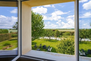 A view from a window overlooking a well-maintained garden with outdoor seating and a clear sky. - Gite Phare - Moulin du Cher: Tranquility Near La Rochelle and the Coast (Chambon)