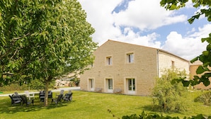 A stone building with a lawn and outdoor seating.