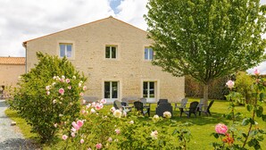 A stone building with a garden, outdoor seating, and a tree.