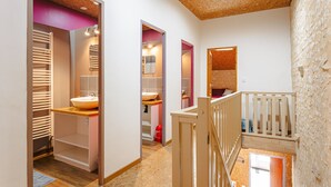 A modern interior with a wooden ceiling, a visible bathroom with a sink and mirror, and a staircase with a railing.