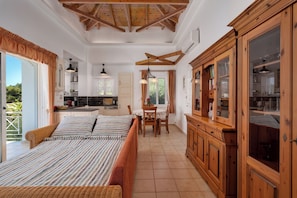 A spacious bedroom with a large bed, a wooden wardrobe, and a dining area with a table and chairs. - Vrisoules pool villa (Methoni)