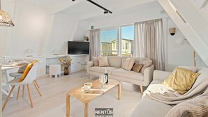 A modern living room with a sofa, coffee table, and TV. There is a dining area with chairs and a table. - Casa Ibiza - family comfort Dunepark Oostduinkerke (Oostduinkerke)