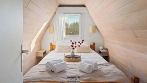 A cozy attic bedroom with a sloped ceiling, a large window, and a bed with neatly folded towels. - Casa Ibiza - family comfort Dunepark Oostduinkerke (Oostduinkerke)