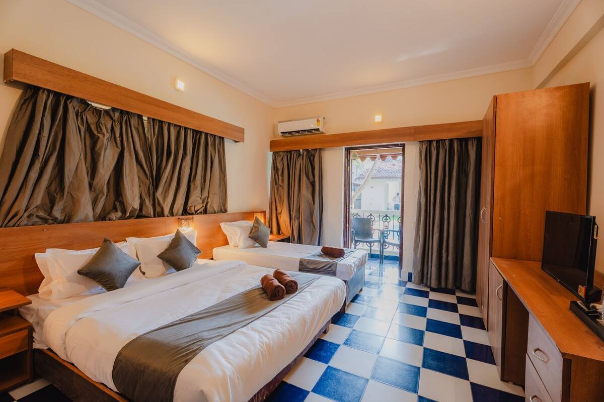 A hotel room with two beds, a TV, and a balcony with a view.