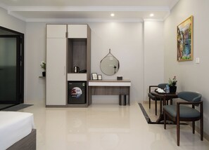 A modern hotel room with a bed, a desk with a mirror, a small seating area, and a wardrobe. - Diamond Light Hotel (Ha Noi)