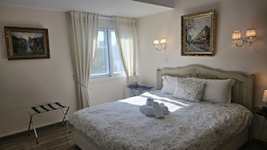 A hotel room with a large bed, two wall-mounted lamps, a window with curtains, and two framed paintings. - 116 NIC 303 - Stay Vintage Central Suites (Nicosia)