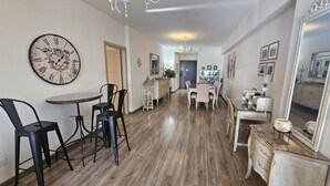 A spacious dining area with a large wall clock, wooden flooring, and a mix of modern and classic furniture. - 116 NIC 303 - Stay Vintage Central Suites (Nicosia)