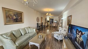 A living room with a sofa, coffee table, TV, and a dining area with chairs and a table. - 116 NIC 303 - Stay Vintage Central Suites (Nicosia)