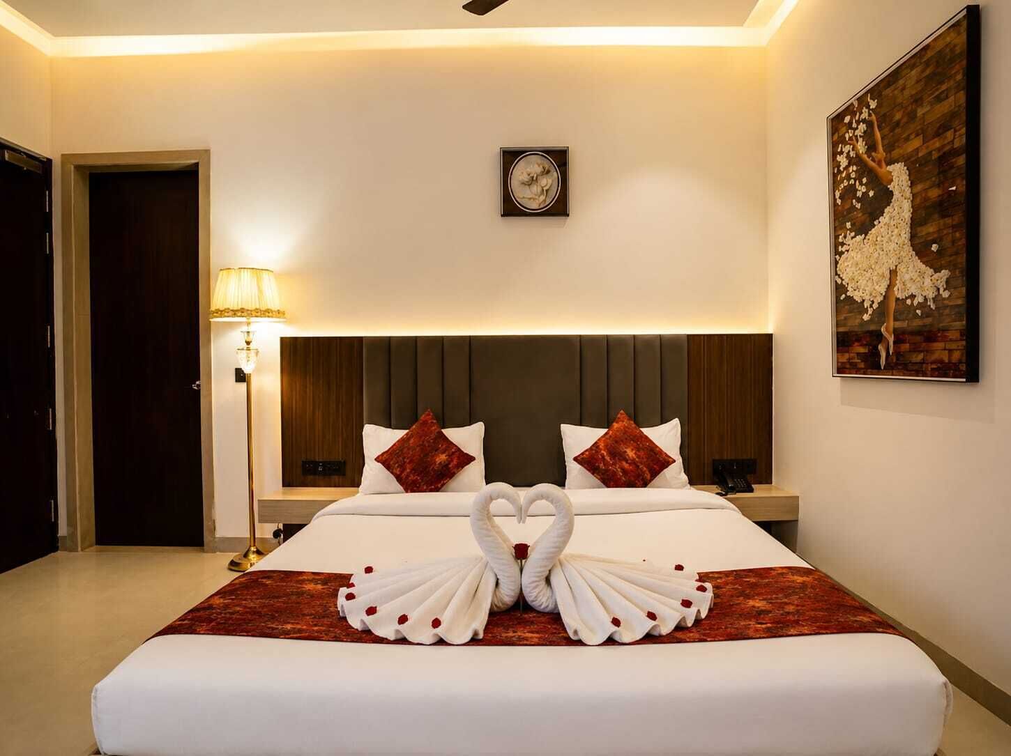 Une chambre d’hôtel avec un lit, une table de chevet, une lampe, une horloge et un tableau.