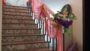 A staircase with patterned tiles, a decorative floral arrangement, and a wall-mounted mirror. - Prince Diamond Boutique Hotel (Varanasi)