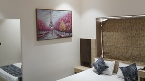A modern bedroom with a bed, a ceiling fan, a painting of the Eiffel Tower, and a large mirror. - Prince Diamond Boutique Hotel (Varanasi)