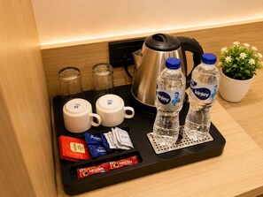 A tray with a kettle, two water bottles, two white mugs, and packets of coffee and sugar. - Prince Diamond Boutique Hotel (Varanasi)