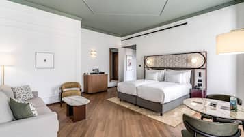 A hotel room with a bed, a desk, a chair, a sofa, and a table.