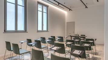A classroom with green chairs and tables, large windows, and a white ceiling.