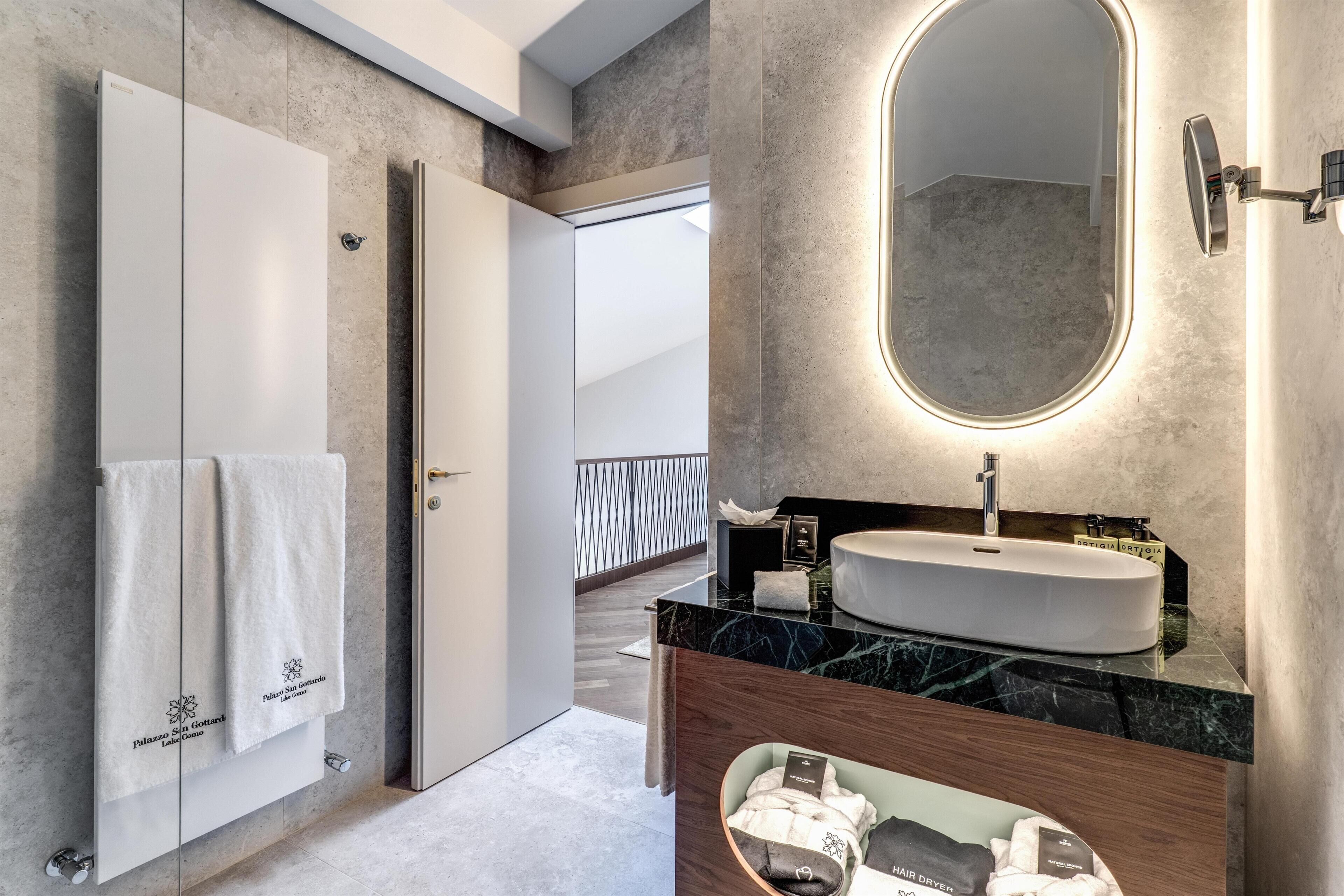 A modern bathroom with a white sink, a large mirror, and a towel rack with two towels.