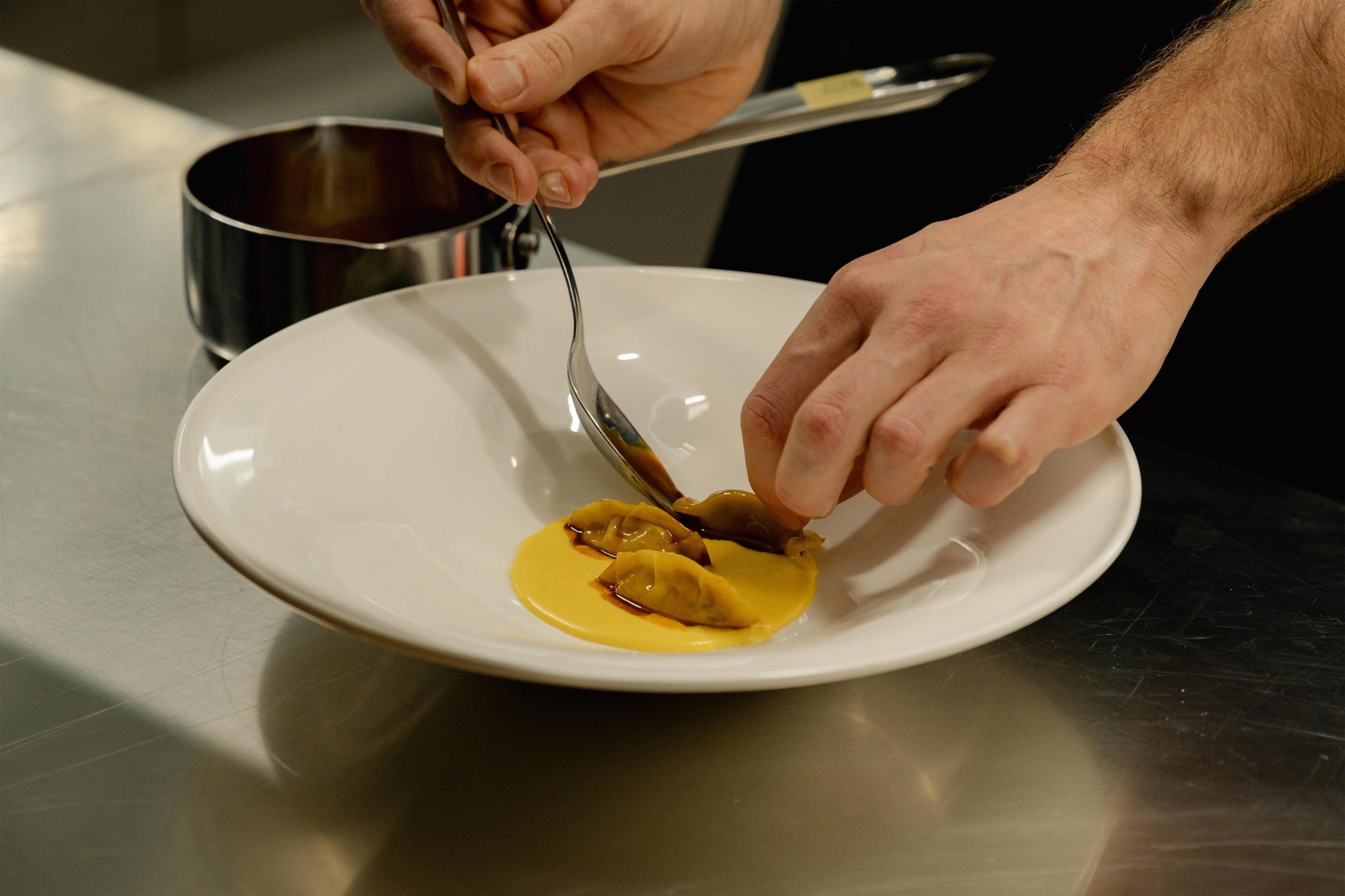 Una persona sirve comida de una olla a un plato.