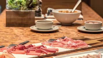 Una mesa de buffet con diversos alimentos, incluyendo carnes cortadas y tazones de sopa.