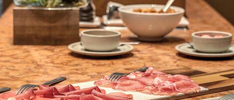 A buffet table with various food items, including sliced meats and bowls of soup.