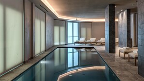 A modern indoor pool area with clear glass walls, lounge chairs, and a minimalist design. - Palazzo San Gottardo Lake Como, a Radisson Collection (Como)