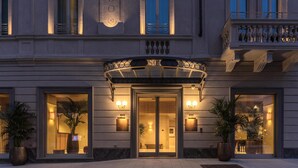 A hotel entrance with a grand archway, large windows, and potted plants. - Palazzo San Gottardo Lake Como, a Radisson Collection (Como)