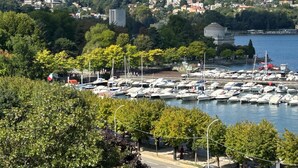 A marina with numerous boats docked, surrounded by lush greenery and residential buildings on a hillside. - Palazzo San Gottardo Lake Como, a Radisson Collection (Como)