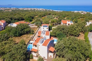 A residential area with multiple houses, a swimming pool, and a view of the sea. - All Season Star Villa (Rethymno)