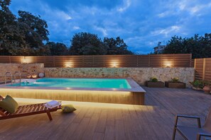 Une piscine dotée d’une terrasse en bois, d’un mur en pierre et d’une clôture en bois.