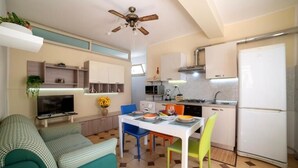 A compact kitchen with a dining table, chairs, and a refrigerator. - House facing the sea in San Saba (Messina)