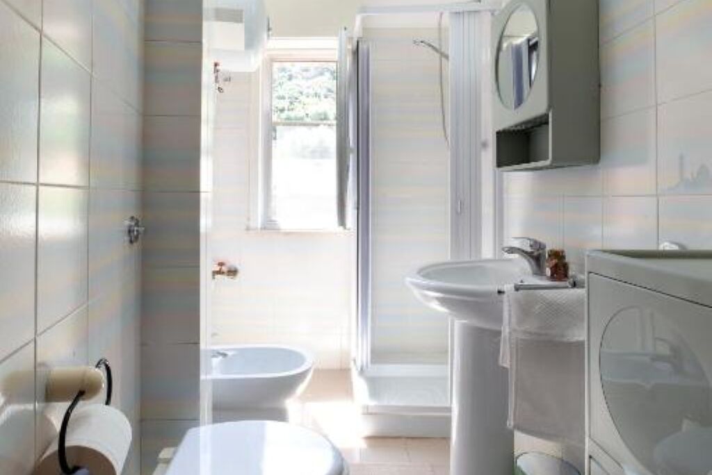 Un baño con inodoro, bidé, lavamanos y espejo.