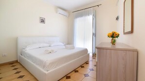 A bedroom with a bed, a wooden cabinet, and a small vase with flowers. - House facing the sea in San Saba (Messina)