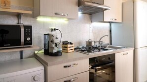 A modern kitchen with a microwave, coffee maker, gas stove, and built-in oven. - House facing the sea in San Saba (Messina)