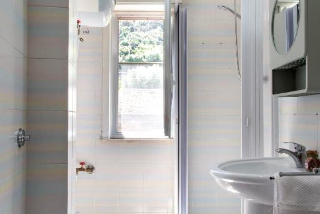 A bathroom with a shower, a sink, and a window.