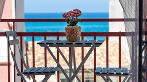 A balcony with a wicker pot containing pink flowers, overlooking a beach. - House facing the sea in San Saba (Messina)