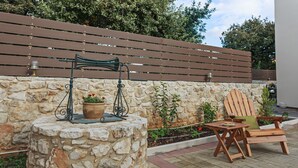 A stone wall with a wooden bench and a table with a potted plant. - All Season Sun Villa (Rethymno)