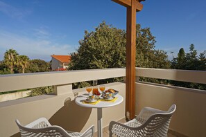 A balcony with a table set for breakfast, including croissants, fruit, and juice. - All Season Sun Villa (Rethymno)