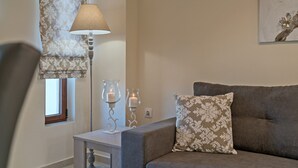 A living room with a sofa, a table with two candles, a lamp, and a window with a curtain. - All Season Sun Villa (Rethymno)