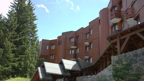 A modern building with multiple balconies and a stone retaining wall. - Renovated studio in Courchevel 1850, ski-in/ski-out, 4 pax, parking included (Courchevel)