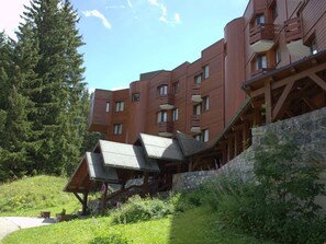 A modern building with multiple balconies and a stone retaining wall. - Renovated studio in Courchevel 1850, ski-in/ski-out, 4 pax, parking included (Courchevel)